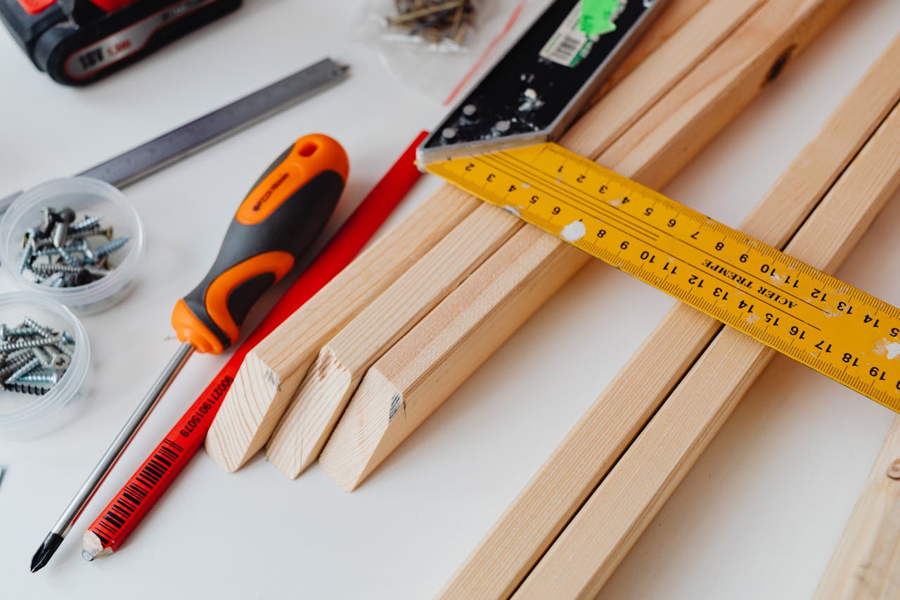A variety of tools including screws, screwdriver, and ruler on a woodworking table.